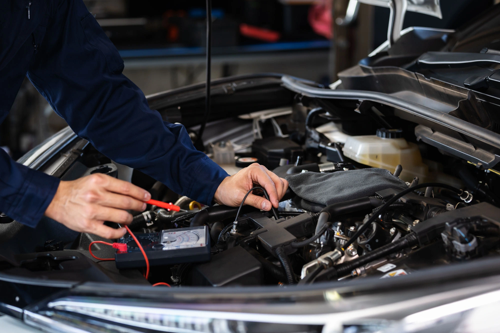 mechanics hand check electrical wiring vehicle system in a car service